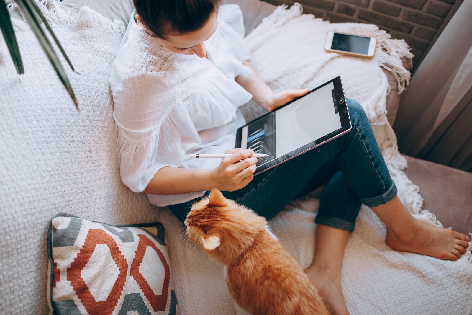 A girl chilling on the couch doing graphic designs.